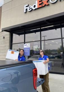 two students in University of Kentucky apparel loading boxes onto the back of a truck outside of FedEx