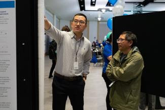 a photograph of Dr. Douglas Zhang with student and their poster