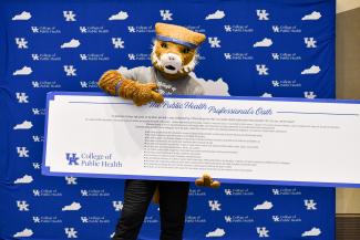 a photograph of the University of Kentucky mascot holding the Public Health Professional's Oath banner
