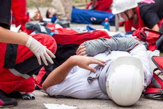 a stock photograph of someone laying on the ground being attended to by emergency medical service workers