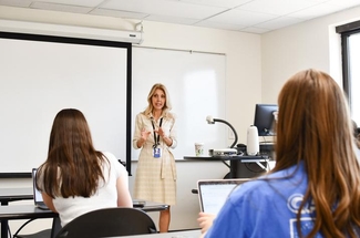 a photograph of Pam Stein in a classroom talking to students