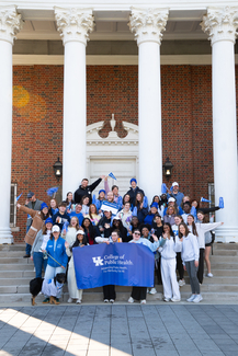  A large, enthusiastic group of University of Kentucky College of Public Health students and staff pose with a blue college banner on the steps of Memorial Hall to celebrate National Public Health Week.