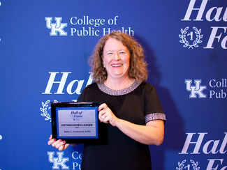 a photograph of Robin Vanderpool at the 2025 Hall of Fame awards holding their "distinguished leader award"