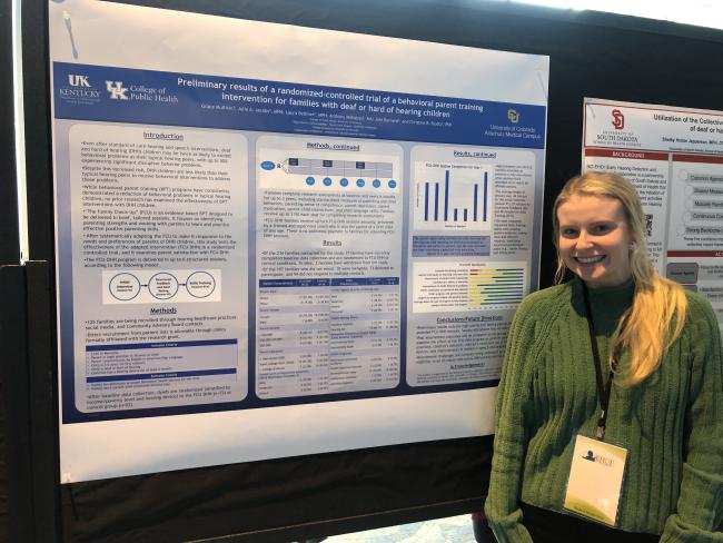 Student Grace Mulliken standing in front of her research abstract