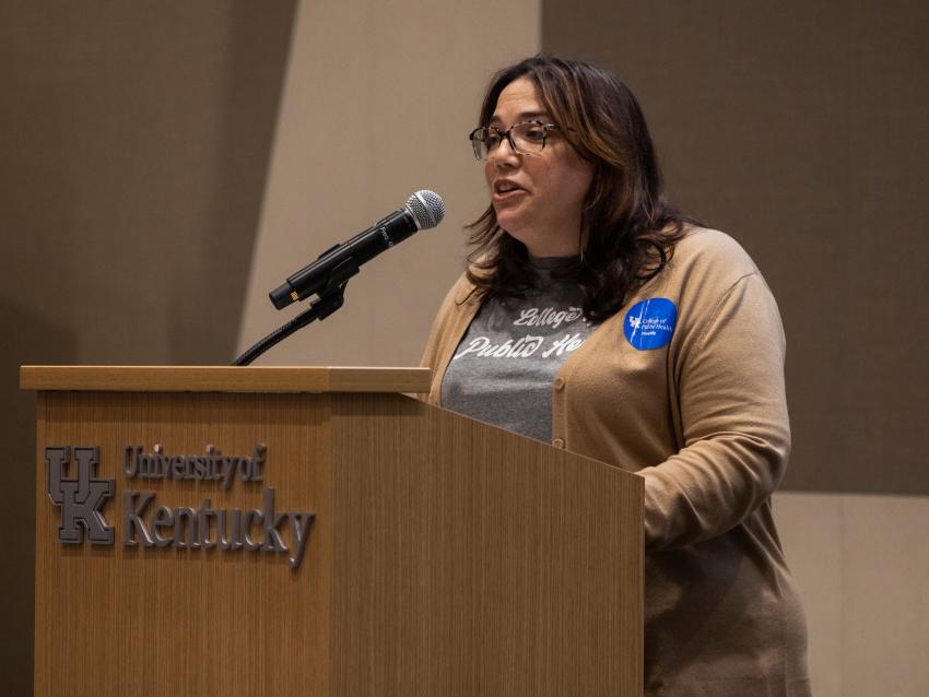 a photograph of Dr. Heather Bush speaking at a podium at the Pump It Up event