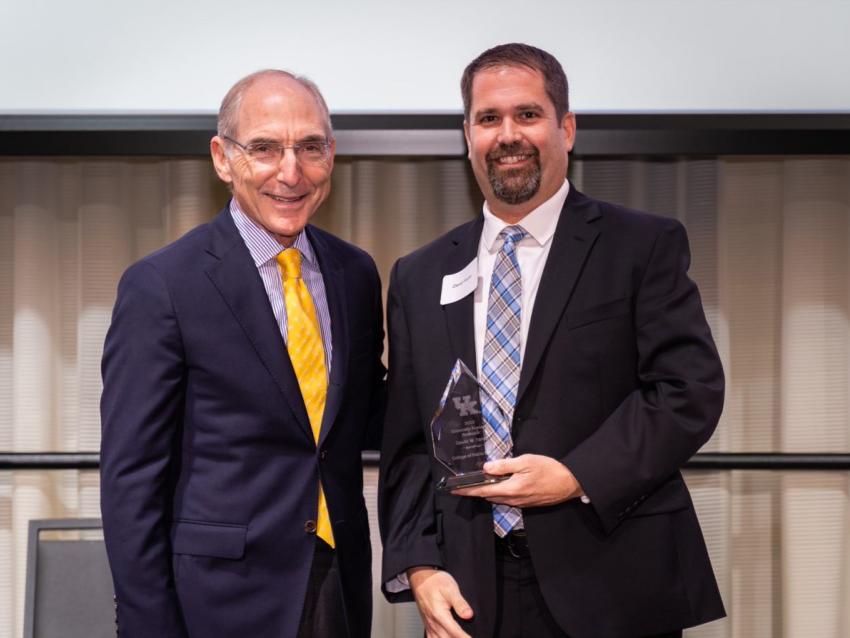 a photograph of Dr. Dave Fardo holding the "2022-2023 UK Research Professorship Award" with President Capilouto