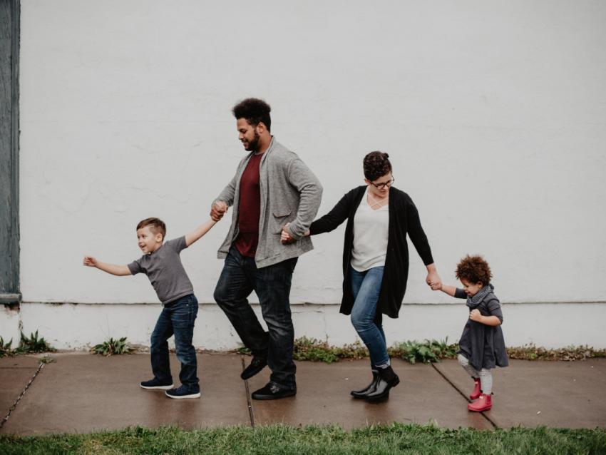 a photograph of a family walking hand-in-hand along a sidewalk