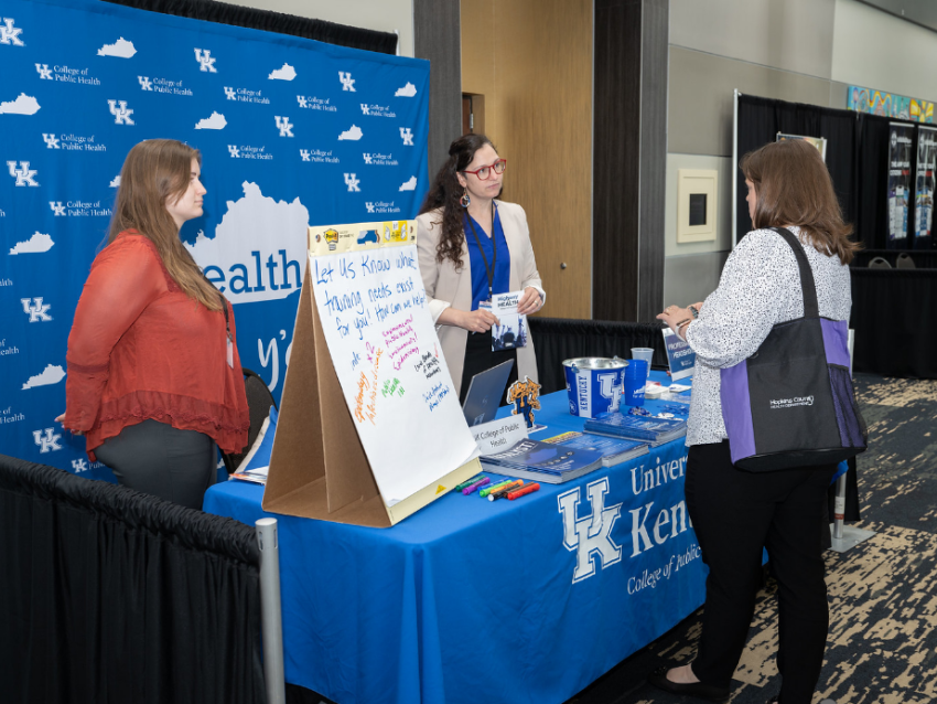 Pictured is Janie Cambron behind a booth speaking to an attendee at the 2022 KPHA Spring Conference