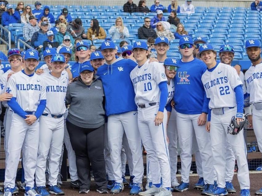 a photograph of Dr. Heather Bush posing with the UK Baseball team