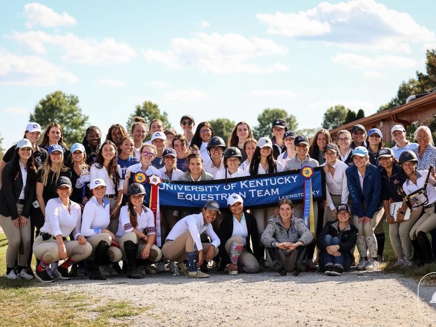 a photograph of the entire University of Kentucky Equestrian Team posing with their banner and medals