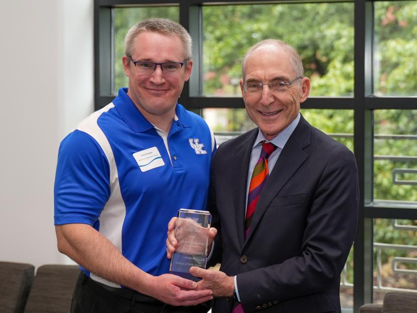 a photograph of Phillip Westgate posing with their award alongside Eli Capilouto