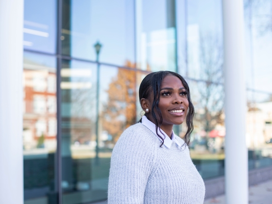 a photograph of a student posing outside a campus building