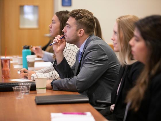 a photograph of students in business attire sitting at a desk