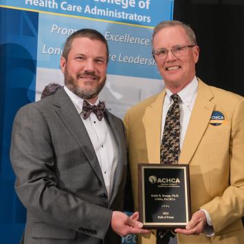 Dr. Keith Knapp (right) receiving plaque award & gold blazer from board chair Matt Lessard (left)